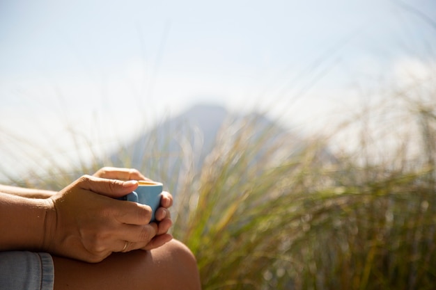 woman on mountains holding a mug with her hands