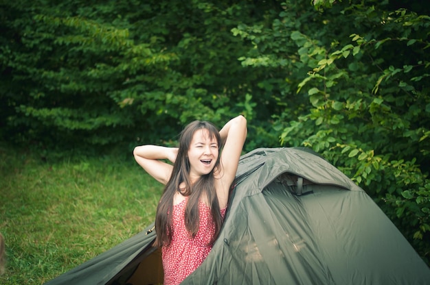 テントの近くの山の中の女性は自然を楽しんでいます