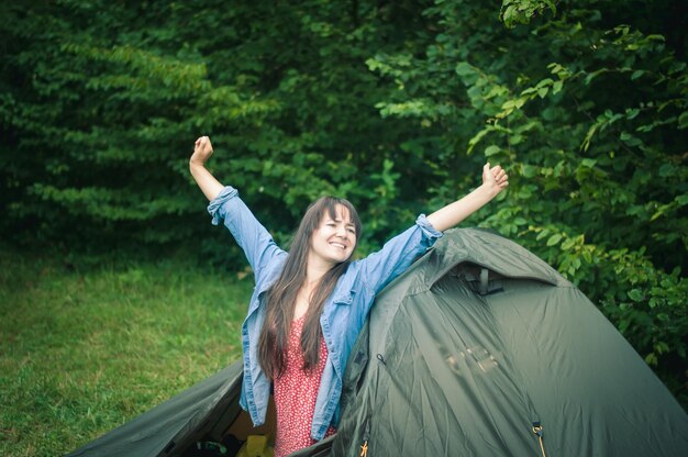 woman among the mountains near the tent enjoys nature