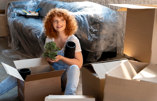 Woman moving in to new home and sorting cardboard boxes with belongings