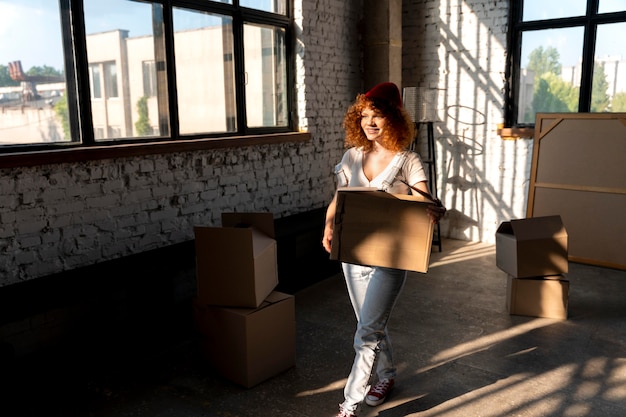 Woman moving in to new home and sorting cardboard boxes with belongings