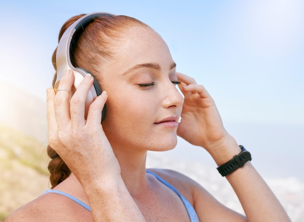 Musica per donna e podcast zen durante la meditazione nella natura rilassarsi e calmarsi con vista sul cielo blu radio benessere e yoga da parte di una ragazza che si gode una pausa con audio rilassante durante un allenamento fitness da solo in estate