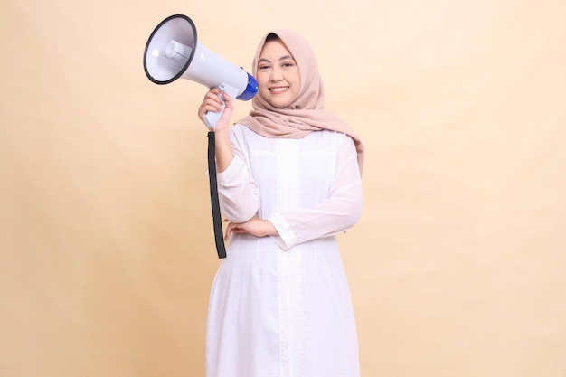 woman muslim asian in hijab looking at the camera smiling cheerfully holding a loudspeaker megaphone