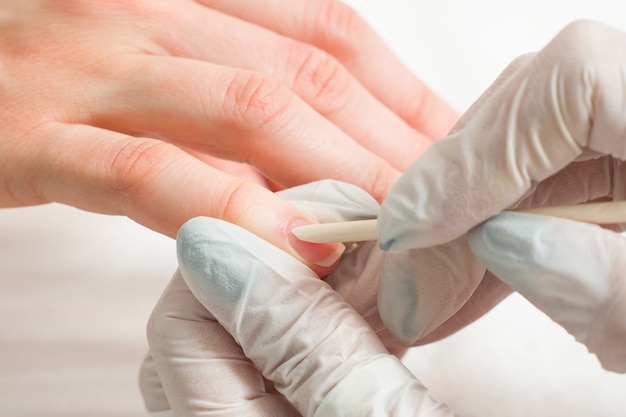 Woman in a nail salon receiving a manicure by a beautician with nail file beauty and hand care