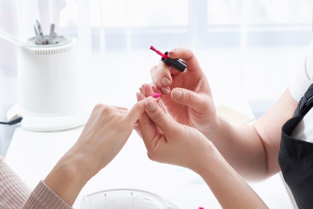 Photo woman in a nail salon receiving a manicure by a beautician with nail file. woman getting nail manicure. beautician file nails to a customer.