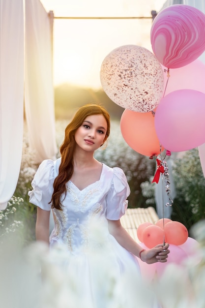 Woman in nature flowers field posing with balloons