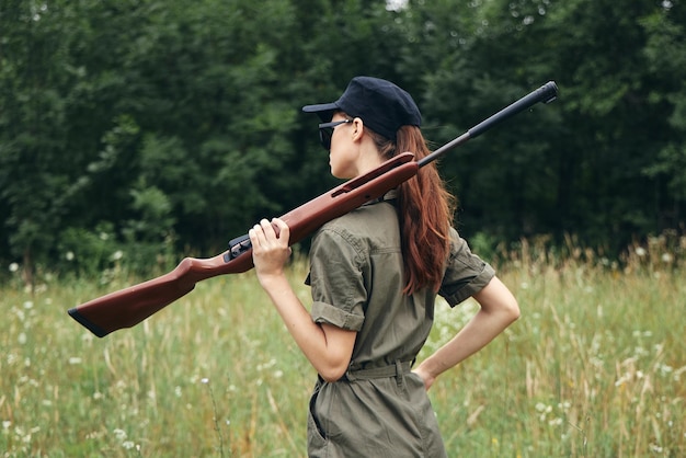 自然の女性ハンターの散弾銃は、新鮮な空気の緑の葉を歩く