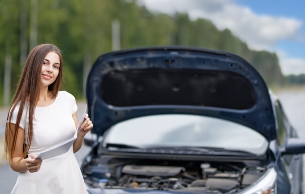 Woman near broken car with opened hood