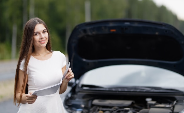 Woman near broken car with opened hood