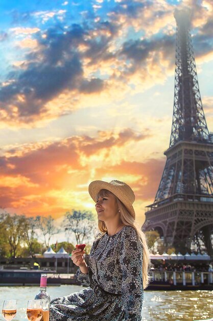 A woman near the Eiffel Tower drinks wine Selective focus