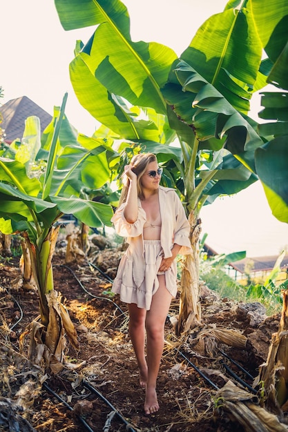 Woman near a large green leaf of a banana tree in nature in the park Tropical plants and attractive girl walking