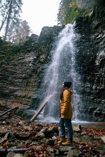 Woman near waterfall in forest autumn season