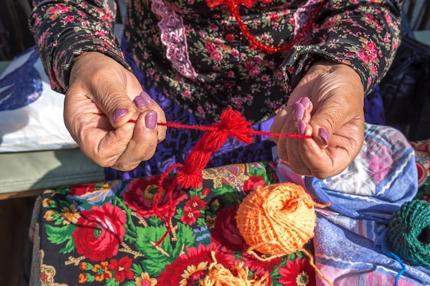 女性針女が糸から古代スラブ人形のお守りを作る