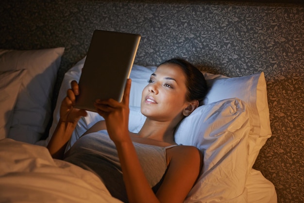 Photo woman night and bed for reading on tablet website or social media app to relax in home hotel or apartment girl mobile touchscreen and happy with ebook movie or video on internet in bedroom
