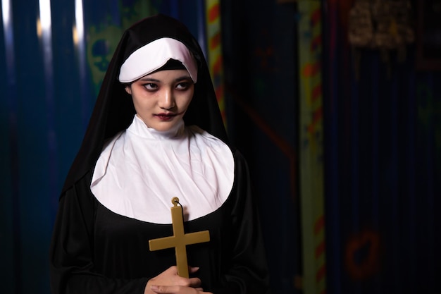 Женщина в монахине на вечеринке в честь Хэллоуина в ночное время. Молодой злой азиатский пуг монахини женщины.
