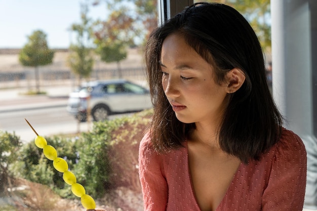 Woman observing carefully a skewer of grapes, close-up horizontal view