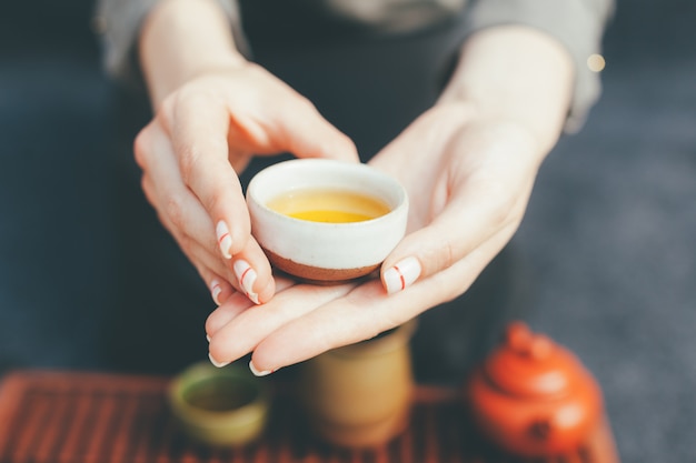 Woman offers hot tea in a vintage ceramic cup.