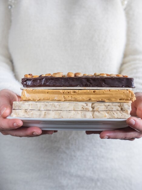 Woman offers tray of chocolate and almond nougat. Typical Spanish food.