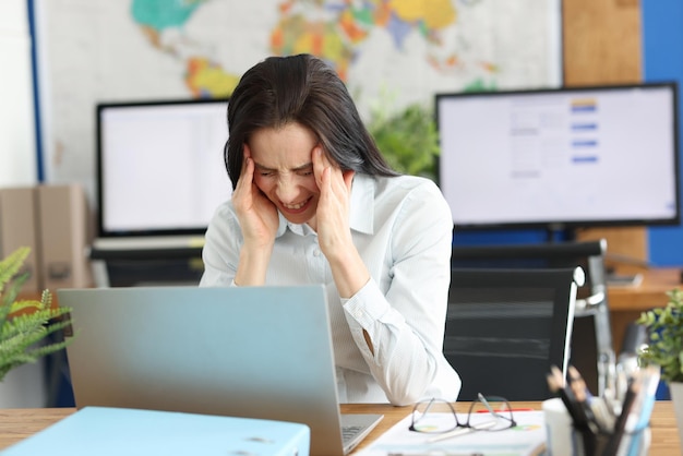 Una donna in ufficio soffre di mal di testa