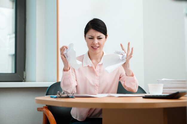 Woman in office with crumpled paper. Office life concept.