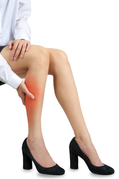 Woman office worker on high heels holding her calf with red highlight in pain area.