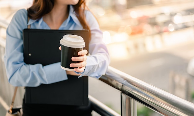 女性サラリーマンは朝、ファイルとコーヒーを持って幸せで新鮮な仕事をします。