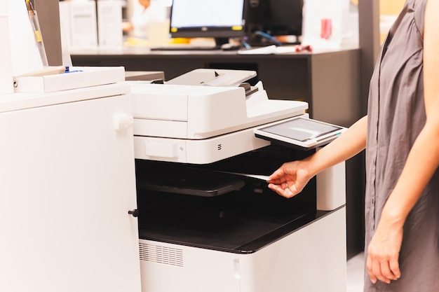 사진 여성 공무원 은 기능적 인 사무실 프린터 에서 종이 문서 를 인쇄 하고 있다