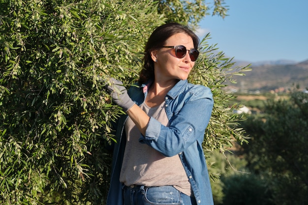 Woman in an olive grove, unripe olive crop