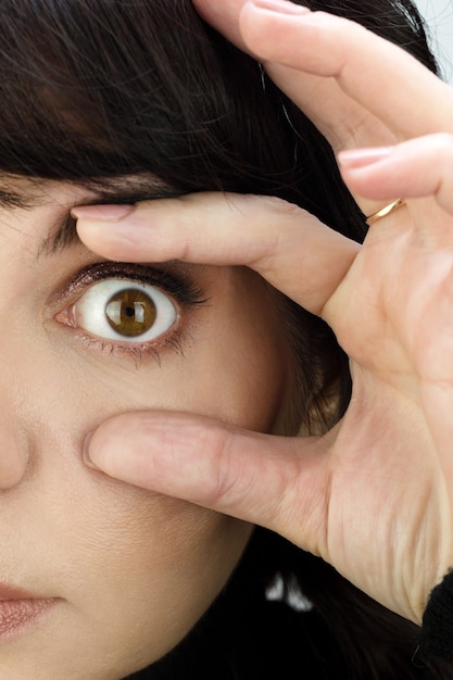 The woman opened her eye wide with her fingers. Close-up