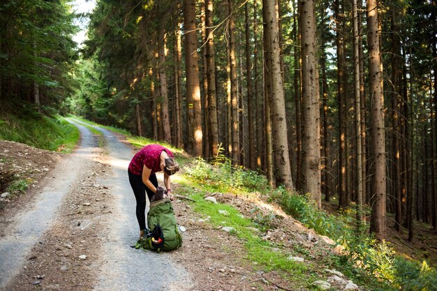 Foto donna che apre la borsa sulla strada tra gli alberi della foresta