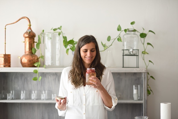 Donna apertura bottiglia di elisir aromatico a base di piante officinali