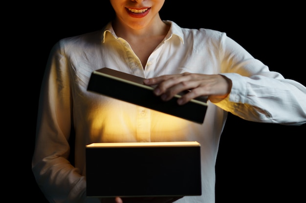 Woman opening a box with gold light mean something exciting inside.