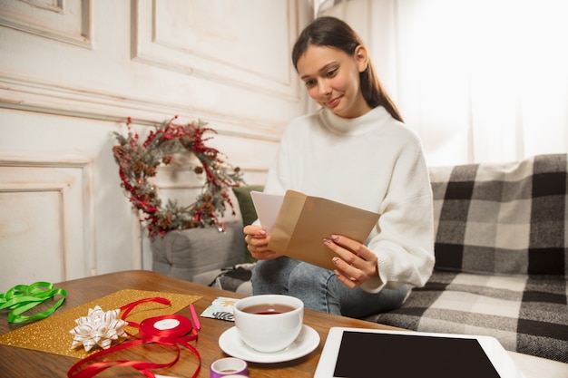 友達から新年とクリスマス202のグリーティングカードを受け取る女性を開きます