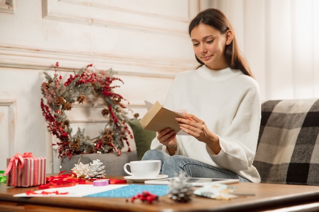 友人や家族から2021年の新年とクリスマスのグリーティングカードを受け取る女性を開く