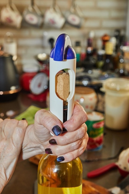 Woman opens bottle of white wine with special corkscrew