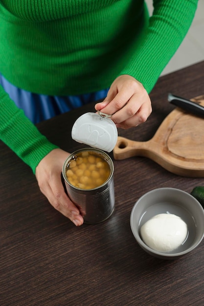 Woman opens can of chickpeas to make salad