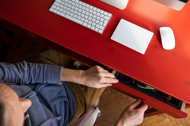 Woman opens a desktop drawer and wants to take something from there on which there is computer