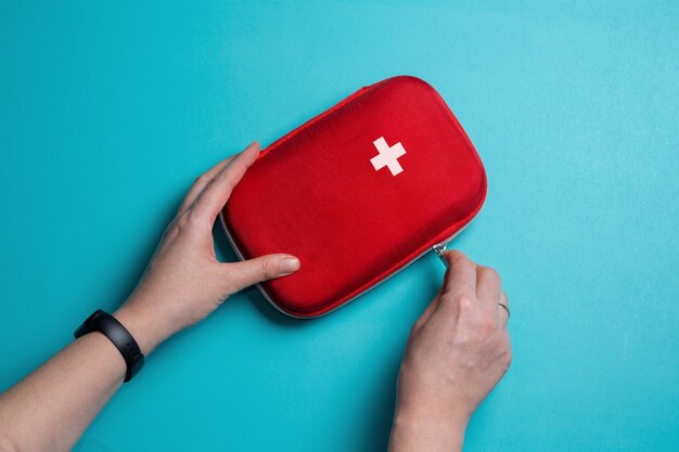 Photo a woman opens a first aid kit home first aid kit on a blue background