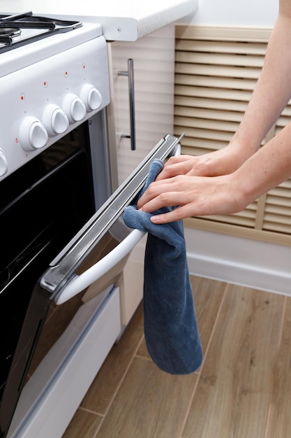 Woman opens the oven in the kitchen closeup