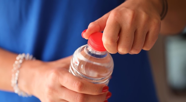 女性が水のクローズアップでプラスチックボトルを開けます 喉のきと飲み物の日常的なコンセプト