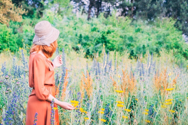 Woman in orande dress is walking in the field