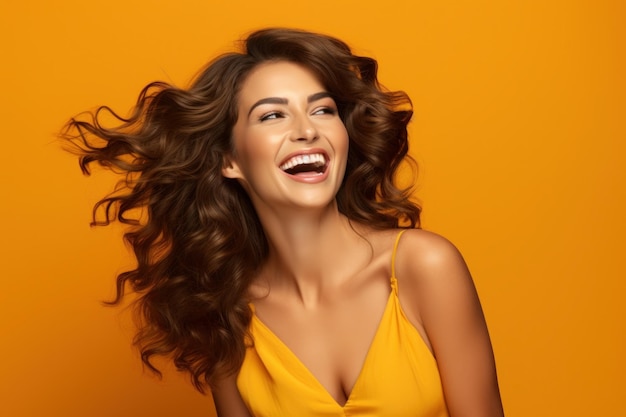 woman in orange attire touching her brown wavy hair Laughing girl posing on yellow background