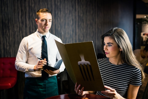 Woman ordering to waiter from the menu in a restaurant