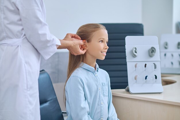 Woman otolaryngologist putting on listening apparatus for kid