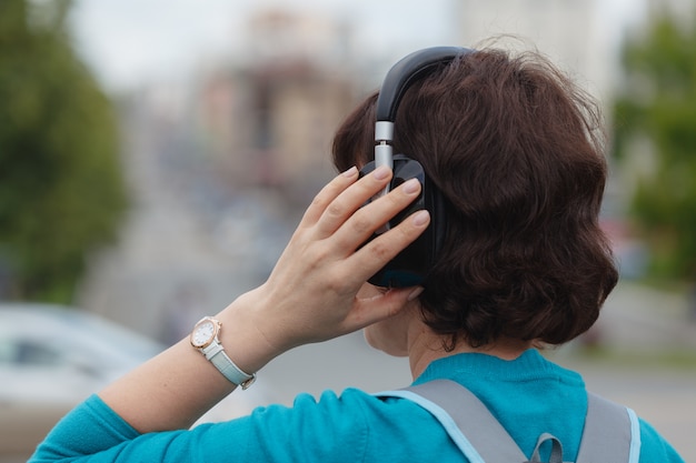 ヘッドフォンで音楽を聴く街で屋外の女性