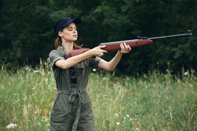 Woman on outdoor Holding a weapon in front of him hunting side views green leaves green