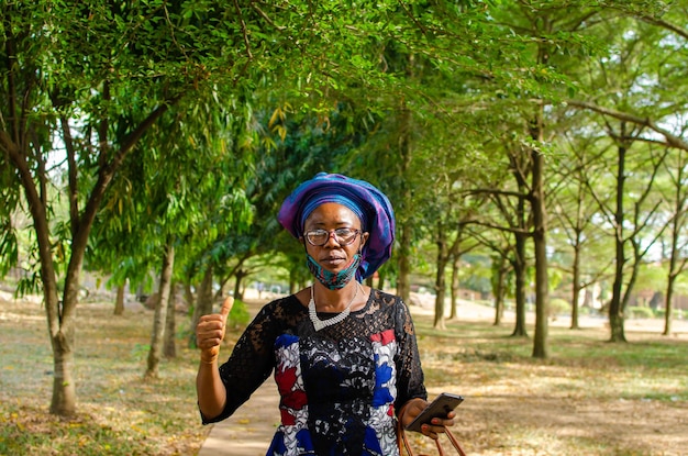 Woman outdoor wearing face mask smiling as she did thumbs up