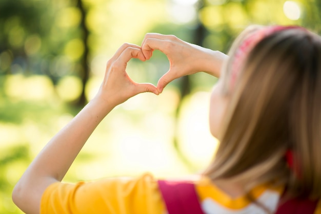 Donna all'aperto che fa un cuore con le mani