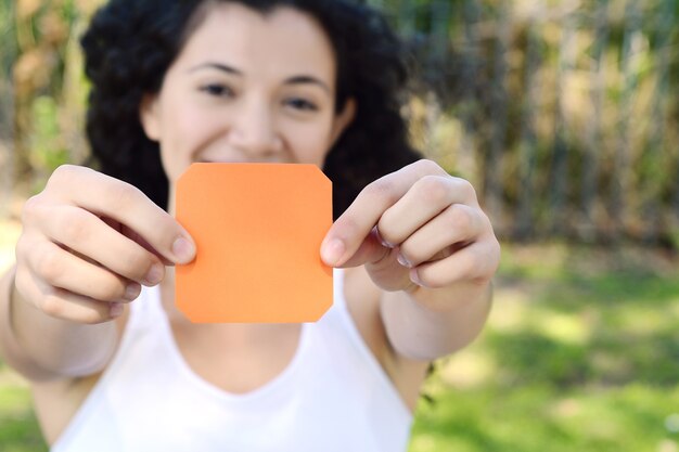 Woman outdoors showing a blank notepad.