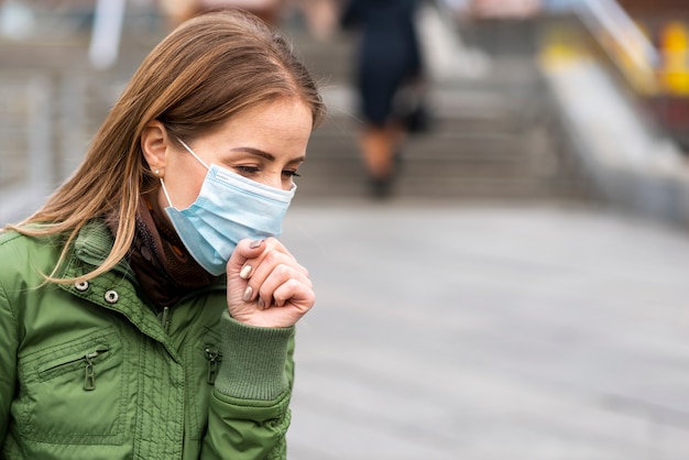 Foto donna all'aperto che indossa una maschera e una tosse di protezione